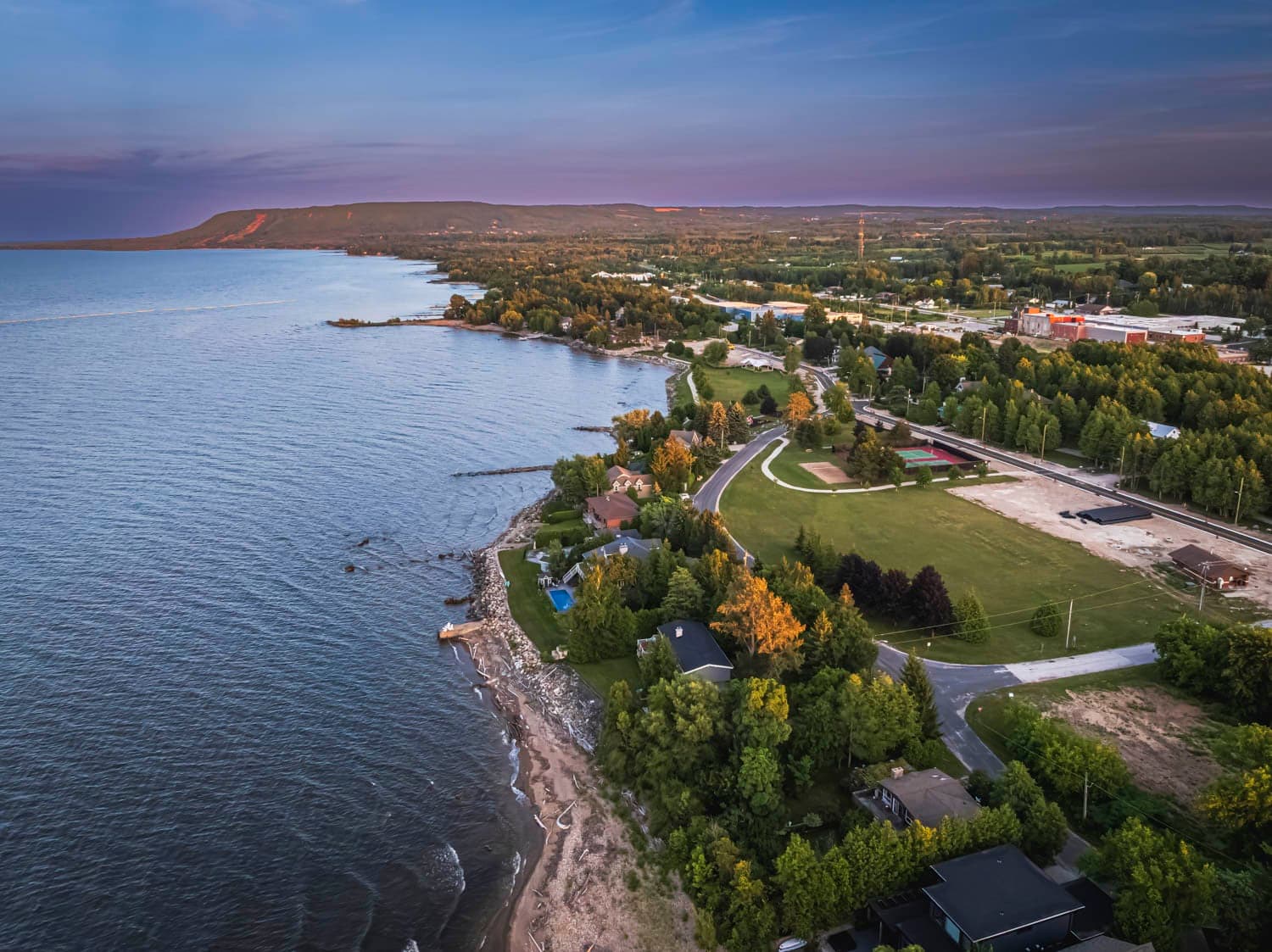 Harbour town at dusk, shoreline curving toward the escarpment